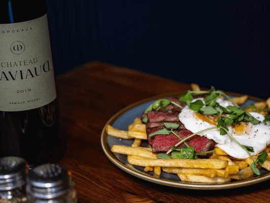 Steak frites with a fried egg on top and a bottle of 2019 Bordeaux at the barrelman dundee