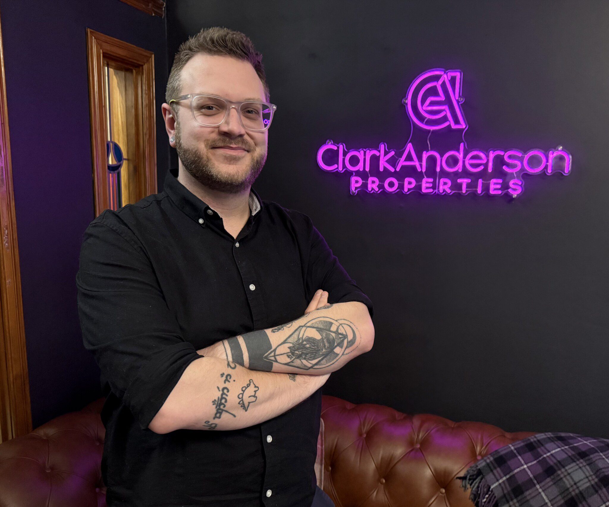 A man stands infront of purple sign which reads 'Clark Anderson Properties'